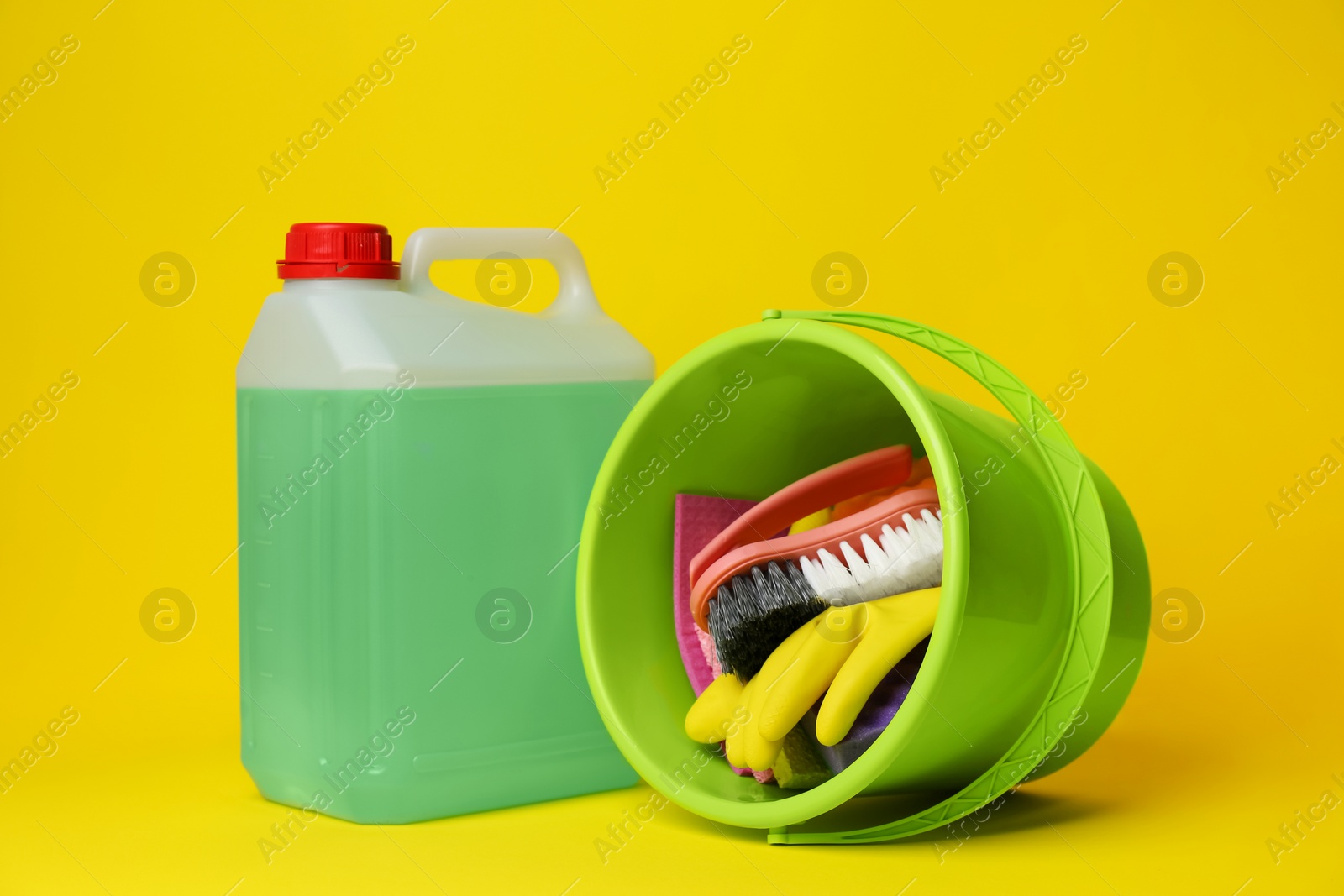Photo of Green bucket, cleaning supplies and tools on yellow background