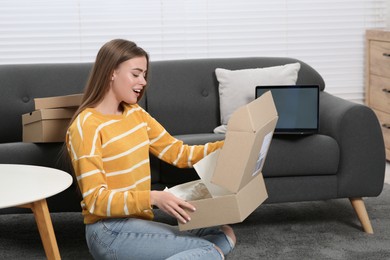 Photo of Emotional woman unpacking parcel at home. Online store