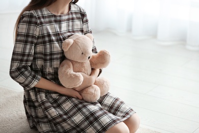 Photo of Upset girl with toy indoors, closeup. Space for text