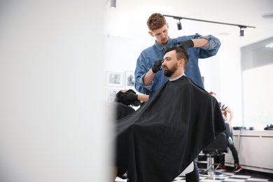 Photo of Professional barber working with client in hairdressing salon. Hipster fashion