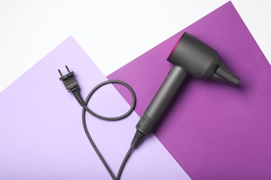 Photo of Hair dryer on color background, top view. Professional hairdresser tool