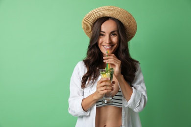 Photo of Young woman with refreshing drink on green background. Space for text
