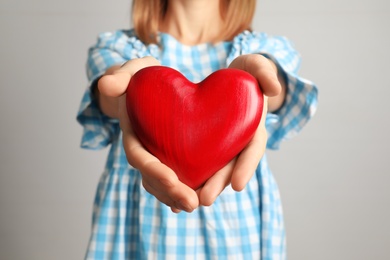 Photo of Woman holding decorative heart on color background, closeup