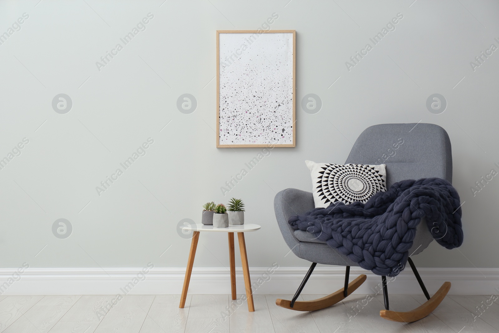 Photo of Knitted merino wool plaid and pillow on rocking chair in room. Space for text