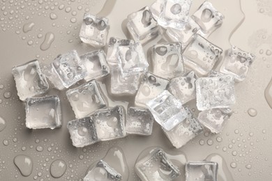 Photo of Melting ice cubes and water drops on light grey background, flat lay