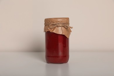 Photo of Tasty canned raspberry jam on white background