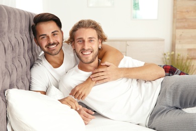 Photo of Happy gay couple on bed at home