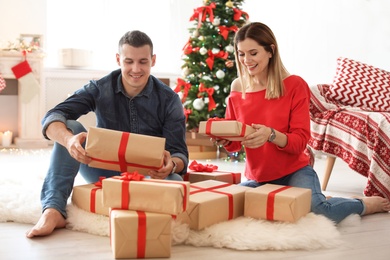 Photo of Young couple with Christmas gifts at home