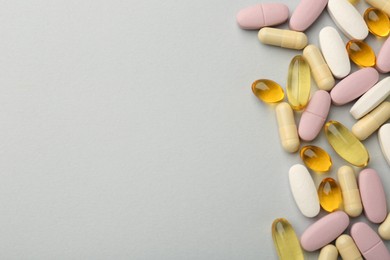 Photo of Different vitamin pills on light grey background, top view and space for text. Health supplement