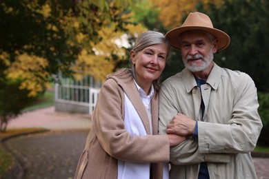 Photo of Portrait of affectionate senior couple in autumn park, space for text