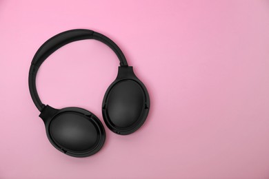 Photo of Modern wireless headphones on pink background, top view. Space for text