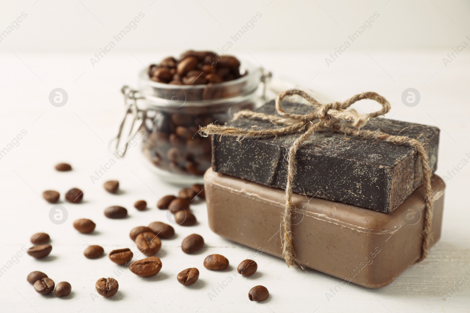 Photo of Handmade soap bars and coffee beans on white table