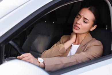 Photo of Young woman suffering from neck pain in her car