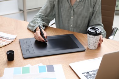Photo of Professional designer with graphic tablet at wooden table, closeup