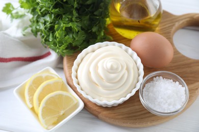 Photo of Fresh mayonnaise sauce in bowl and ingredients on white wooden table, above view