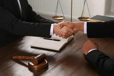 Photo of Law and justice. Notary with client shaking hands at wooden table, closeup