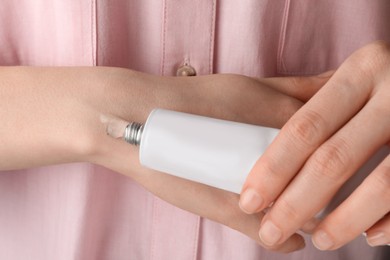 Photo of Woman squeezing out ointment from tube on her hand, closeup