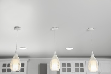Photo of Modern pendant lamps on white ceiling indoors