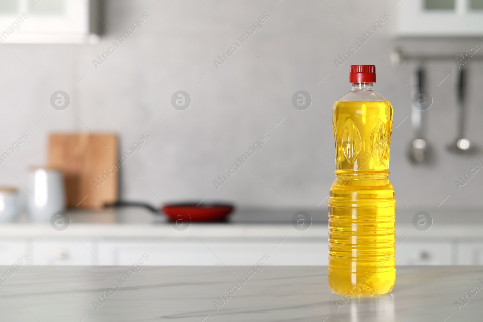 Bottle of cooking oil on white marble table in kitchen. Space for text Photo of Bottle of cooking oil on white marble table in kitchen. Space for text