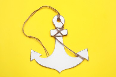 White wooden anchor figure on yellow background, top view