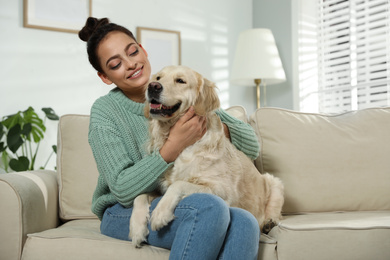 Photo of Young woman and her Golden Retriever on sofa at home. Adorable pet