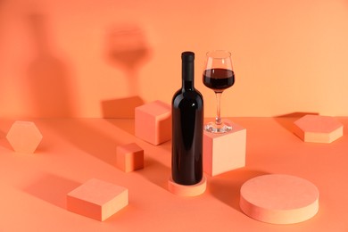 Photo of Stylish presentation of delicious red wine in bottle and glass on orange background