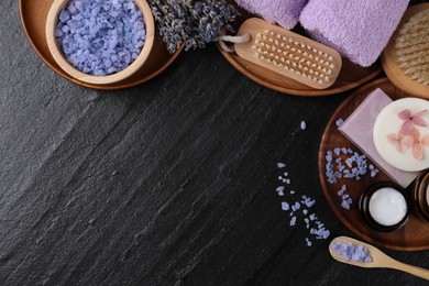 Photo of Flat lay composition with different spa products and lavender on black textured table. Space for text