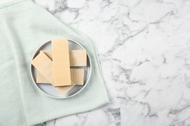 Photo of Plate of delicious wafers on marble background, top view. Space for text