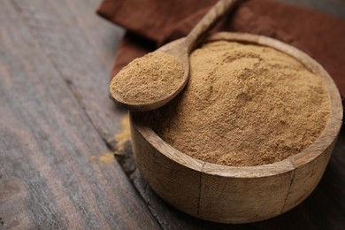 Photo of Dietary fiber. Psyllium husk powder in bowl and spoon on wooden table, closeup. Space for text