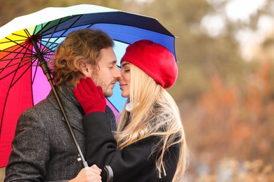 Photo of Young romantic couple with umbrella outdoors on autumn day