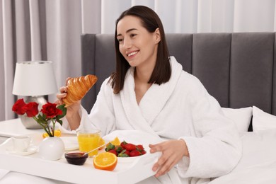 Photo of Smiling woman having breakfast in bed at home