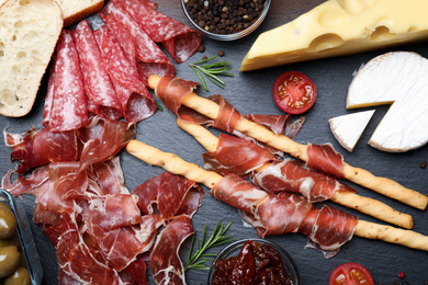 Photo of Tasty prosciutto served on black table, flat lay