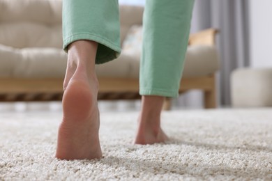 Photo of Woman walking on soft beige carpet at home, closeup