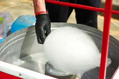 Photo of Man making cotton candy with machine outdoors, closeup