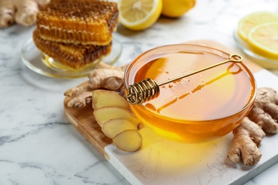 Photo of Honey in bowl and ginger on white marble table. Natural cold remedies