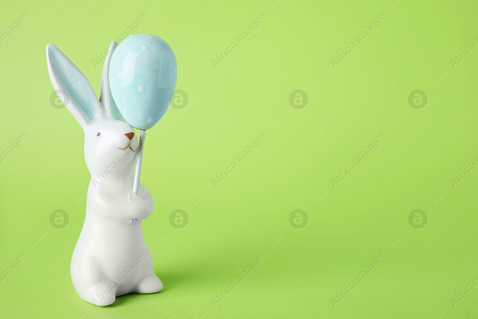 Photo of Easter bunny figure on green background. Space for text