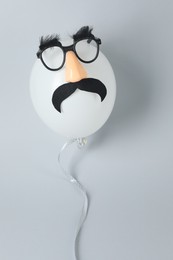 Photo of Man's face made of balloon, funny mask with fake mustache, nose and glasses on grey background, top view