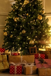 Photo of Gift boxes under Christmas tree with fairy lights indoors