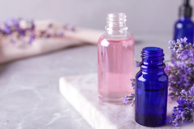 Bottles of lavender essential oil on marble table. Space for text