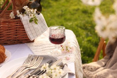 Stylish table setting with beautiful spring flowers and wine in garden