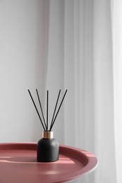 Photo of Aromatic reed air freshener on table indoors, space for text