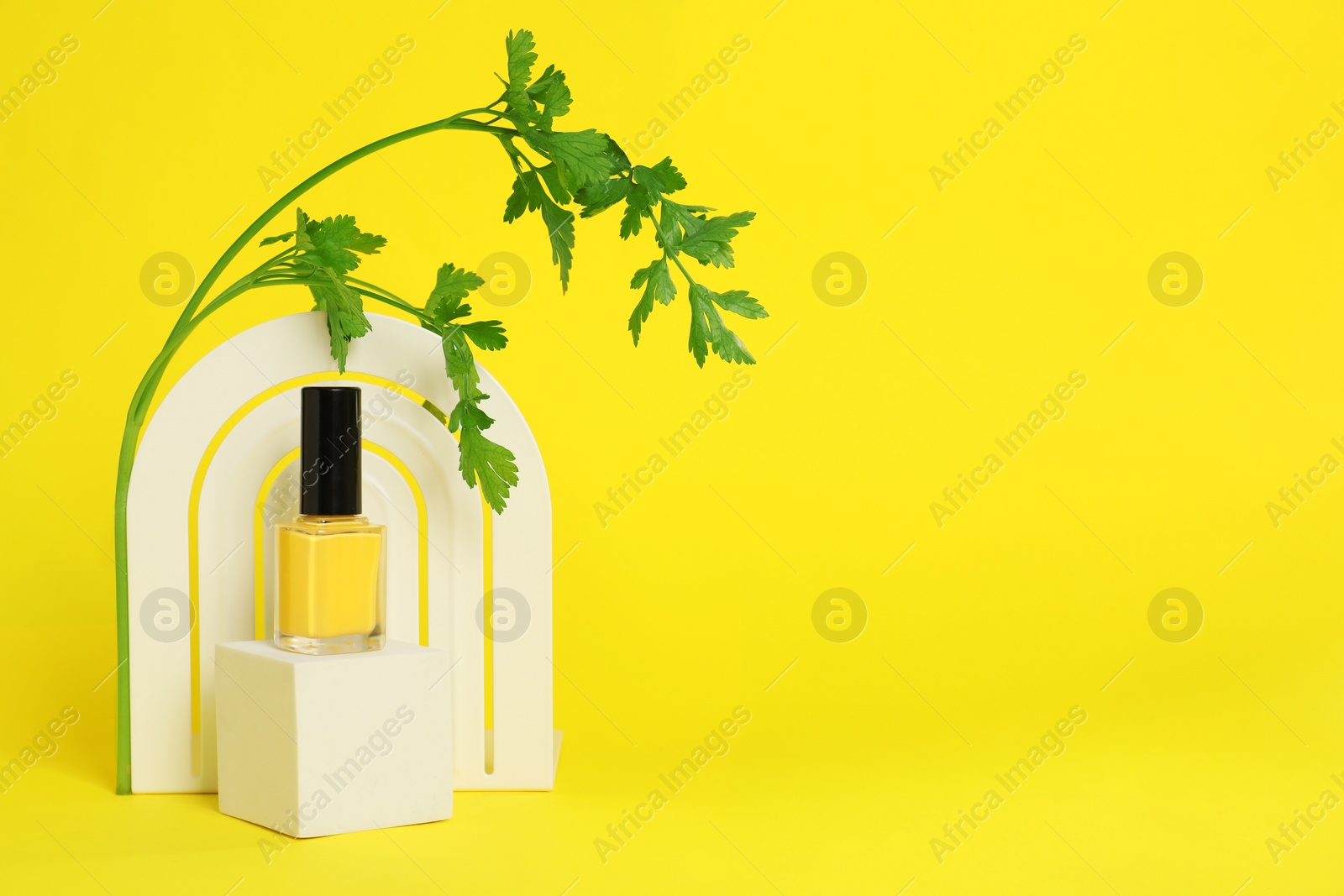 Photo of Stylish presentation of beautiful nail polish in bottle on yellow background. Space for text