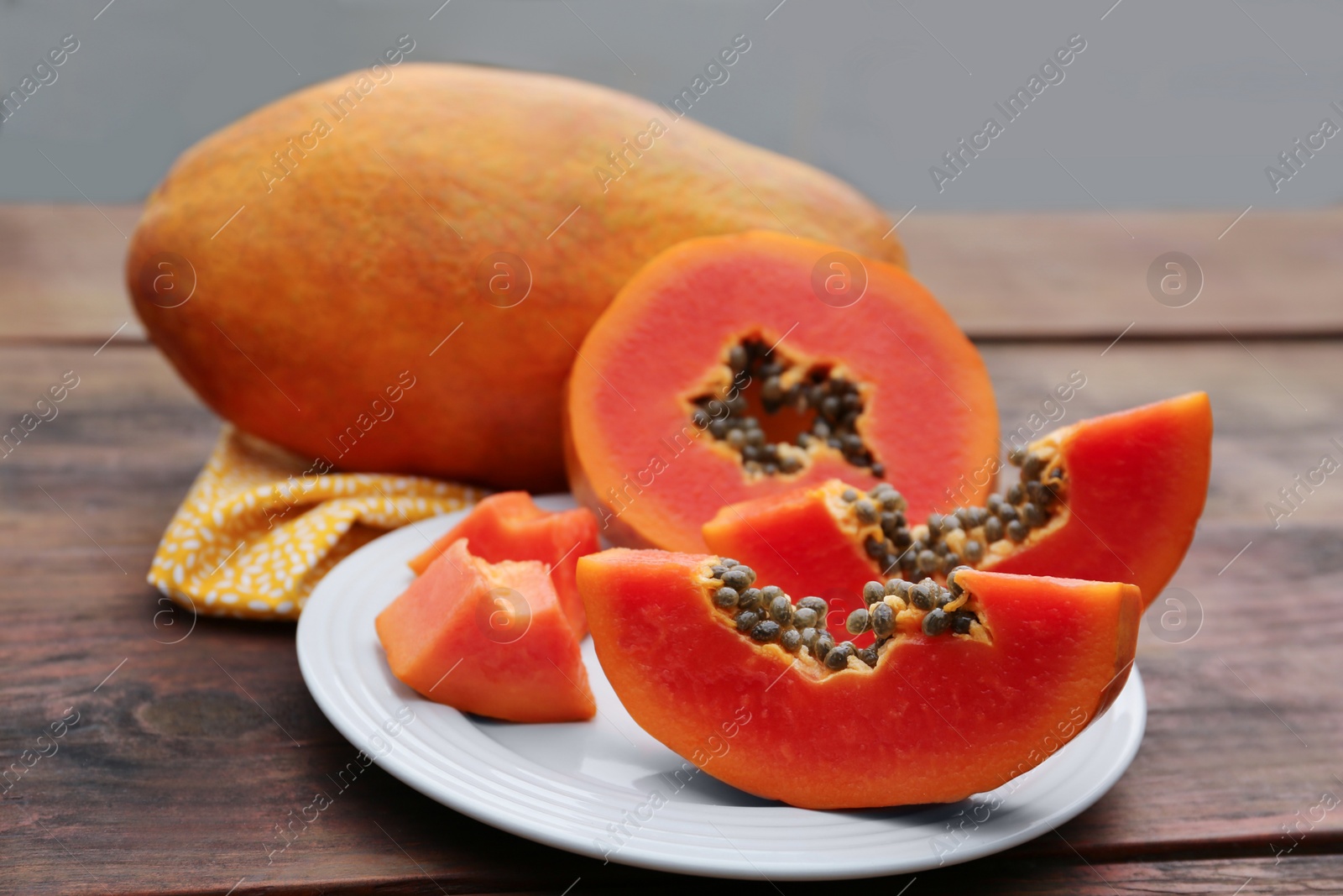 Photo of Ripe cut and whole papaya fruits on wooden table, closeup