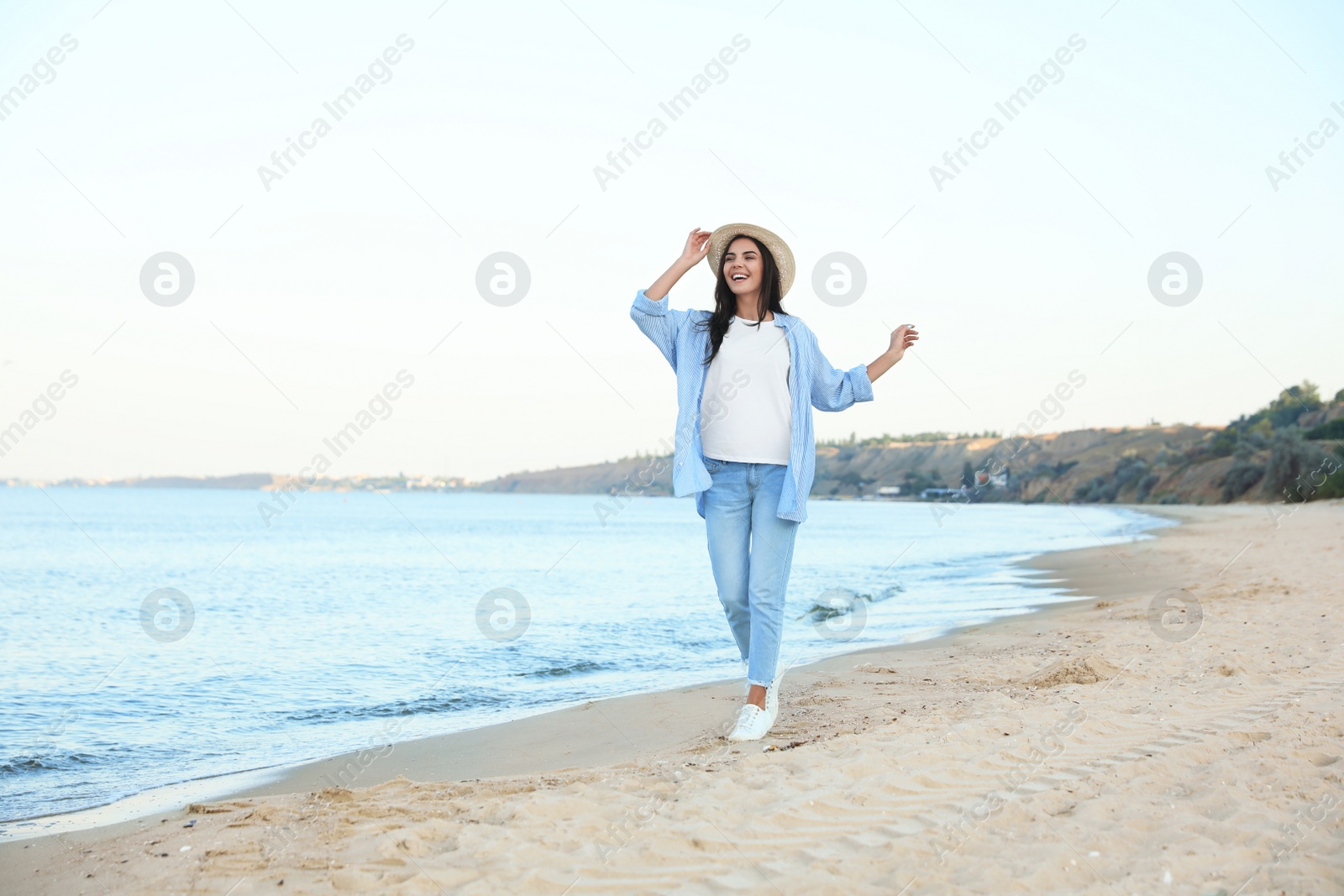 Photo of Beautiful young woman in casual outfit on beach