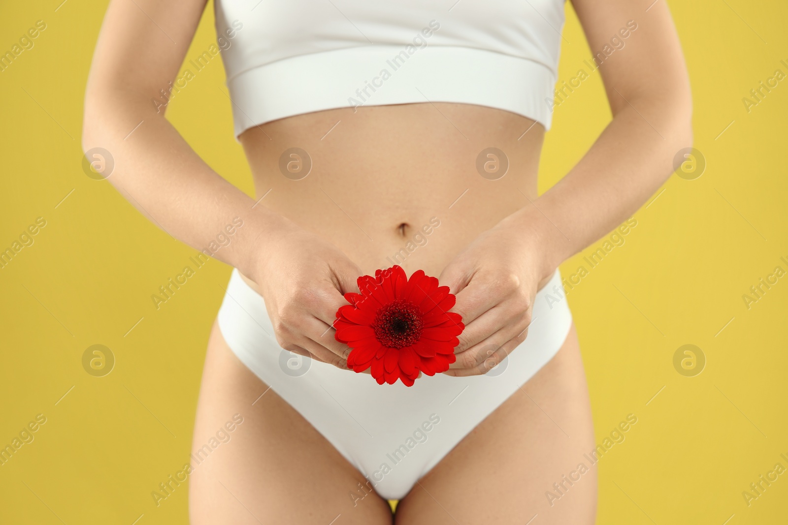 Photo of Gynecology. Woman in underwear with gerbera flower on yellow background, closeup