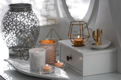 Burning candles in beautiful holders on table indoors