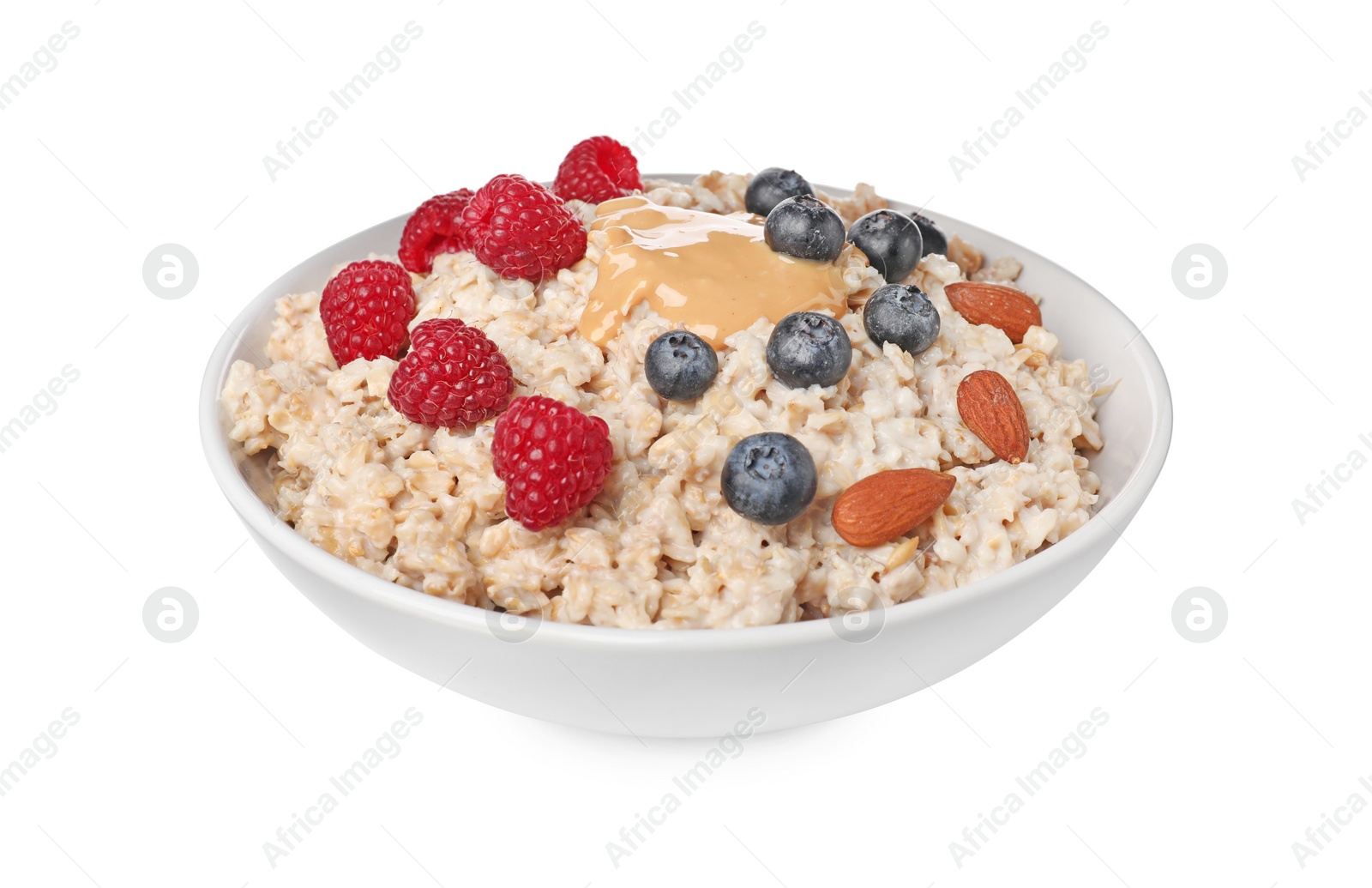 Photo of Tasty boiled oatmeal with berries, almonds and peanut butter in bowl isolated on white