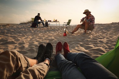 Friends resting on sandy coast, closeup. Beach camping