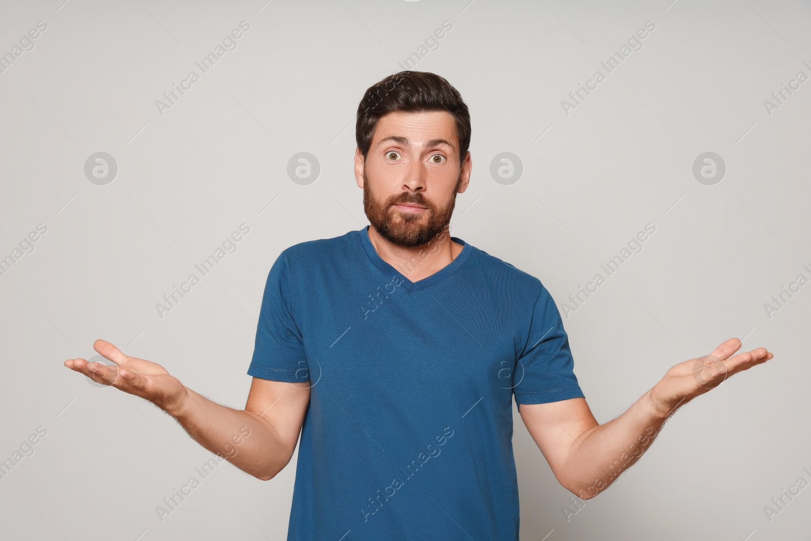 Photo of Handsome bearded man shrugging shoulders on light grey background