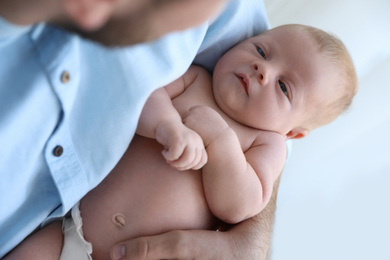 Photo of Father holding his cute newborn baby at home, closeup